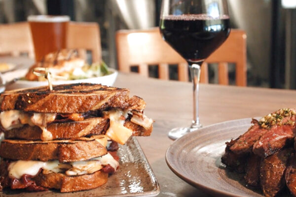 Turkey Rueben with glass of wine on table eat Cork & Barrel